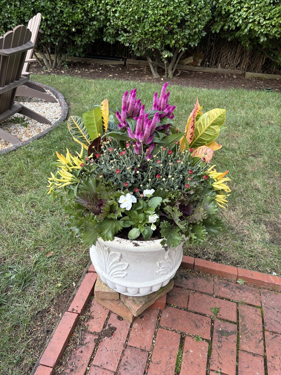 White urn with seasonal flowers on a brick patio