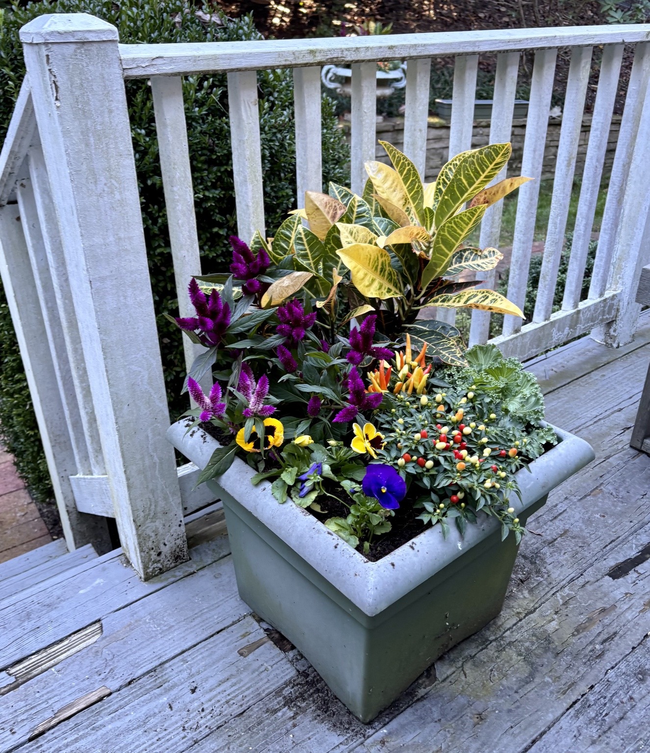 Colorful rectangular fall planter on a wooden deck beside white railings