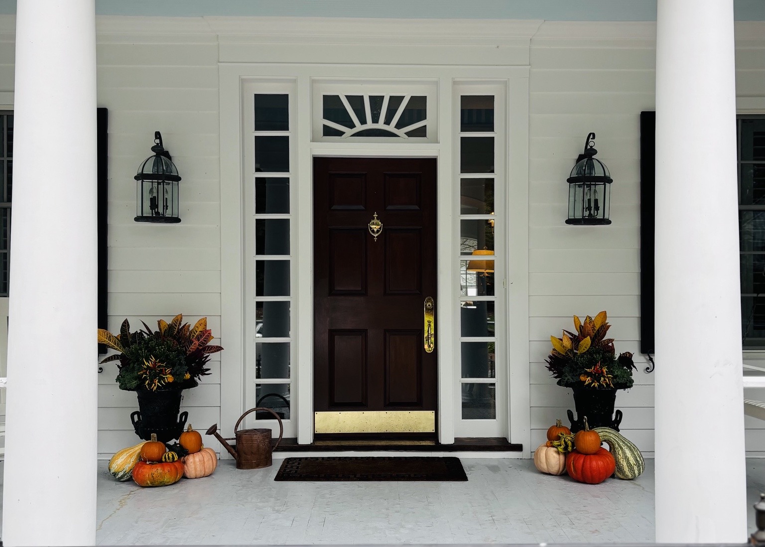 Wide view of a front porch with matching autumn planters and pumpkins