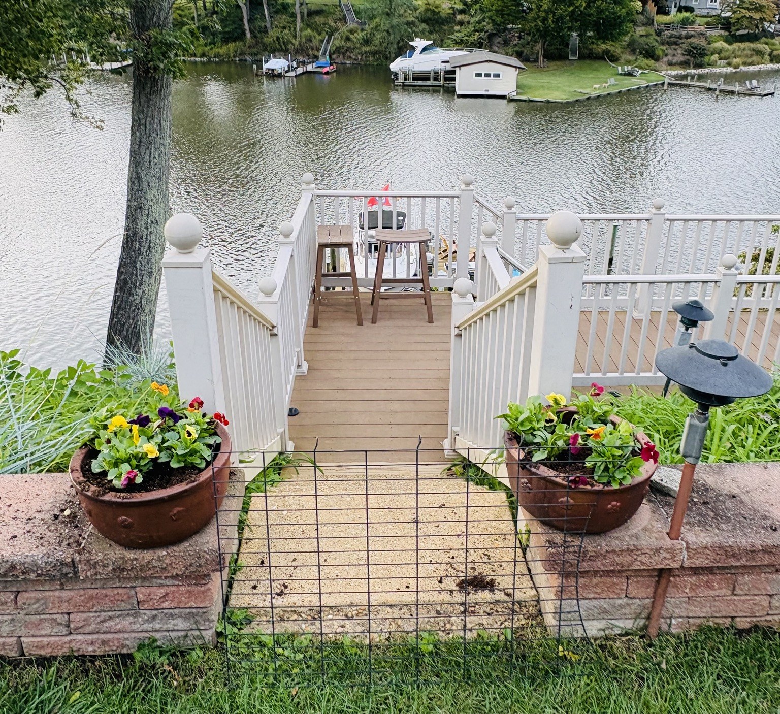 Matching terracotta planters with colorful pansies beside a waterside stairway