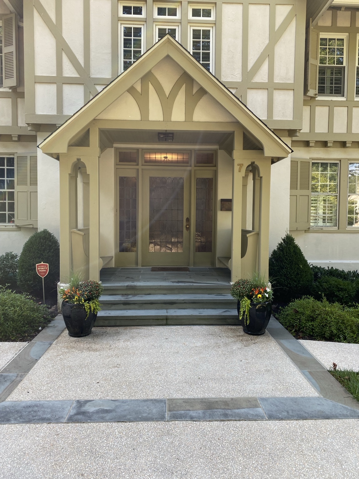 Full view of a Tudor-style entry with matching black fall planters