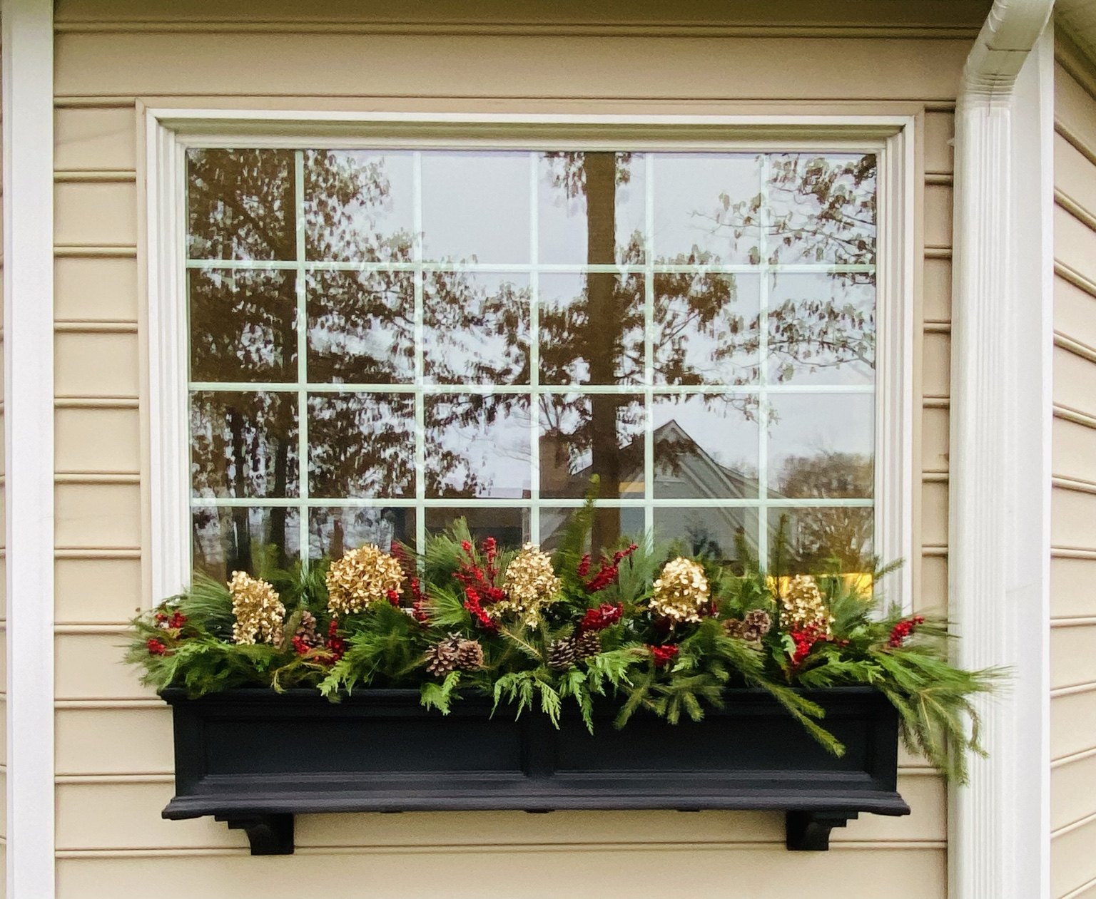 Long holiday window box filled with evergreen branches and seasonal accents