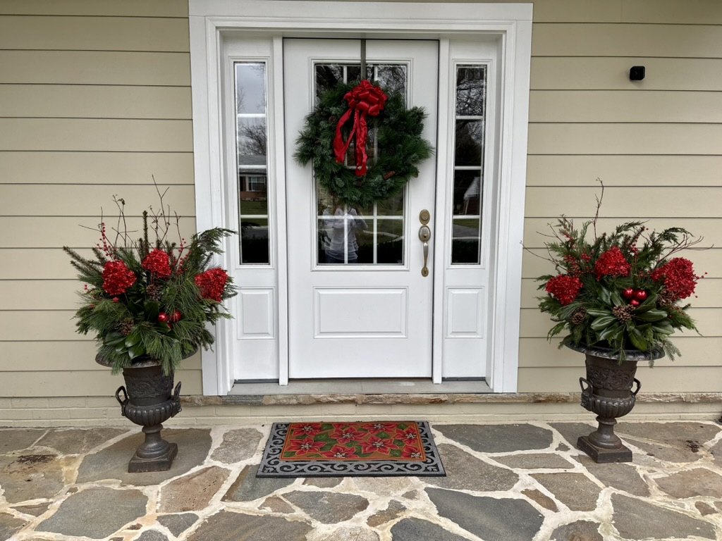 Matching holiday urns flanking a white front door