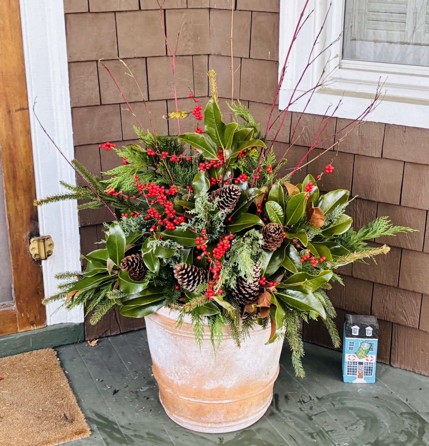 Full evergreen holiday arrangement in a warm terra cotta planter