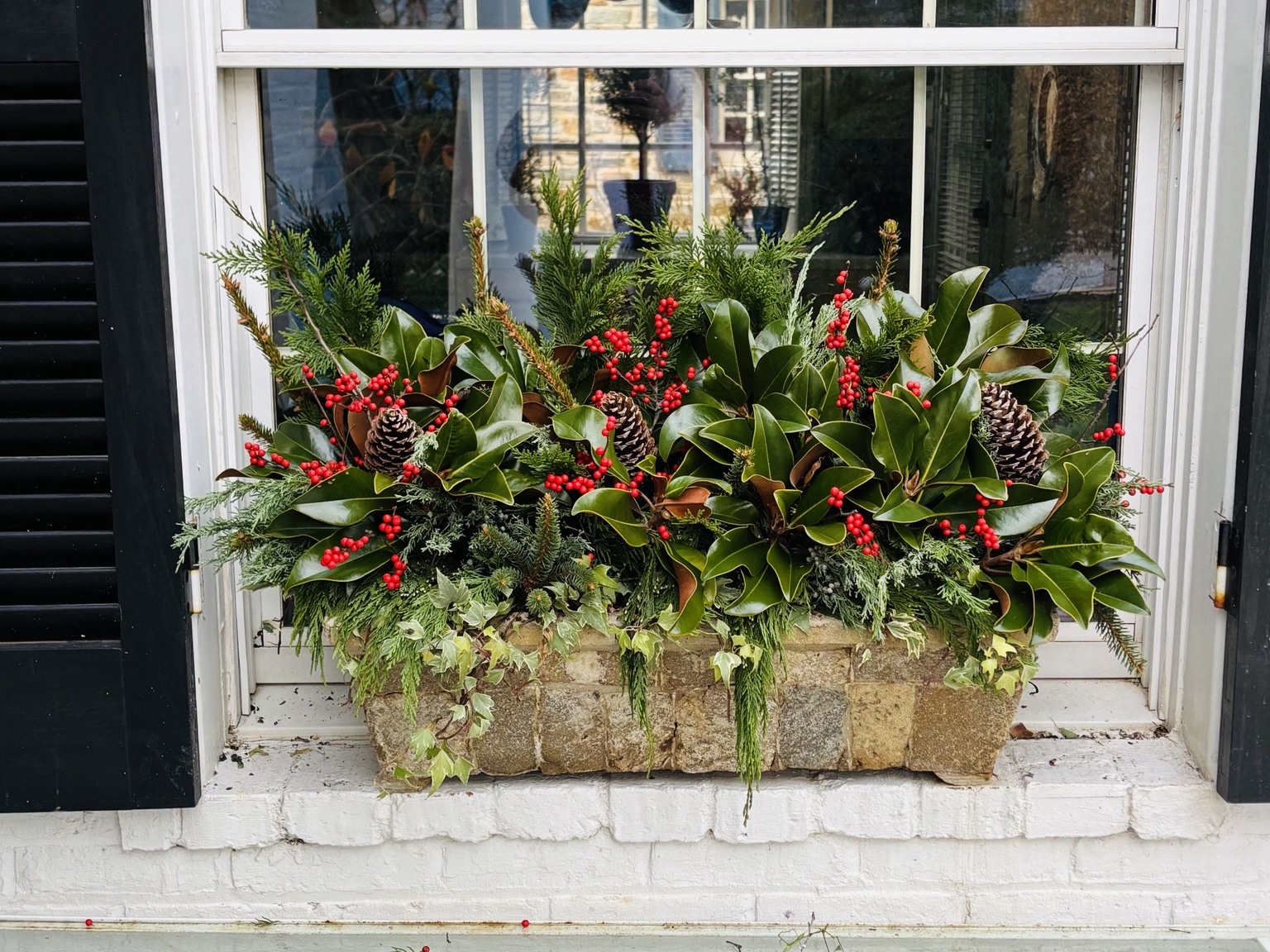 Long holiday window box filled with evergreen branches and berries