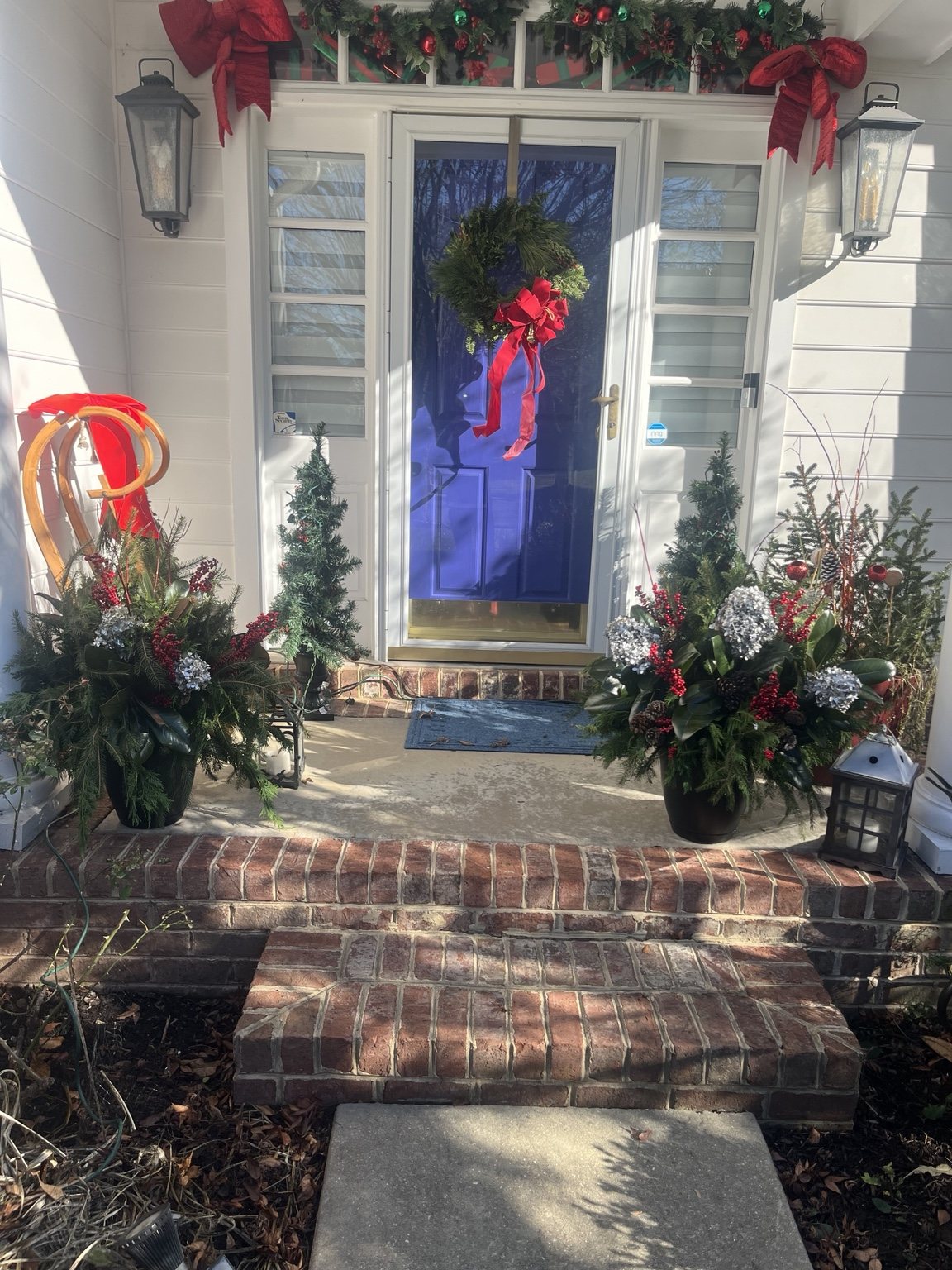Holiday wreath and seasonal planters at a blue front door