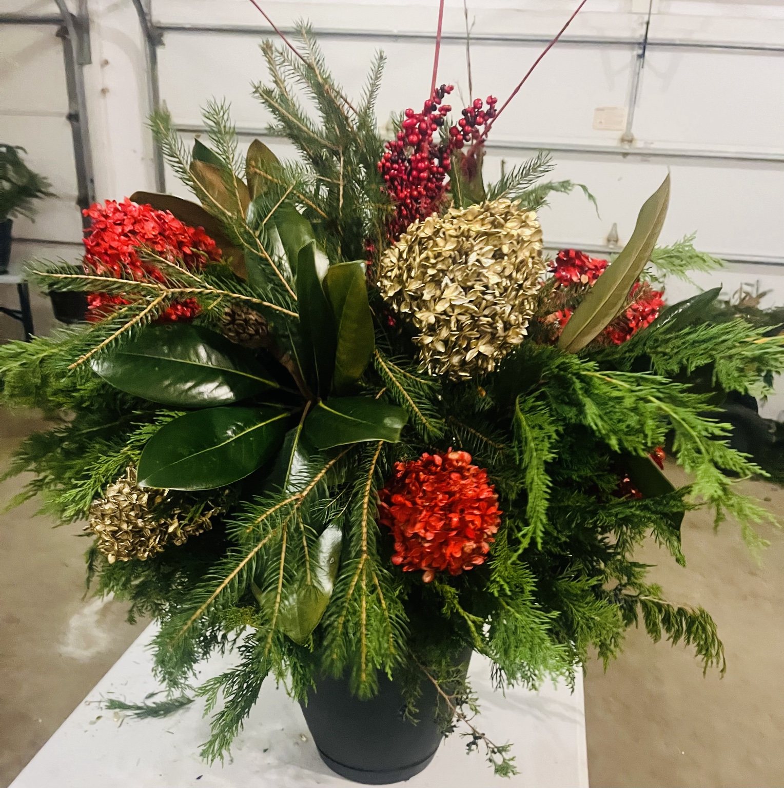 Close view of holiday arrangement with evergreen, berries, pine cones, and magnolia leaves
