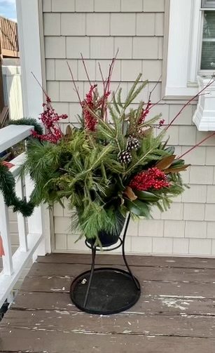 Raised holiday planter with evergreen branches, red berries, and pinecones