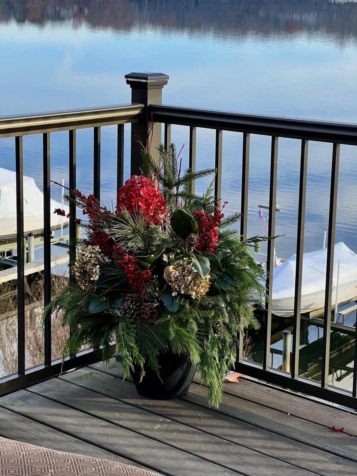 Holiday planter with evergreens, berries, and hydrangeas overlooking the water