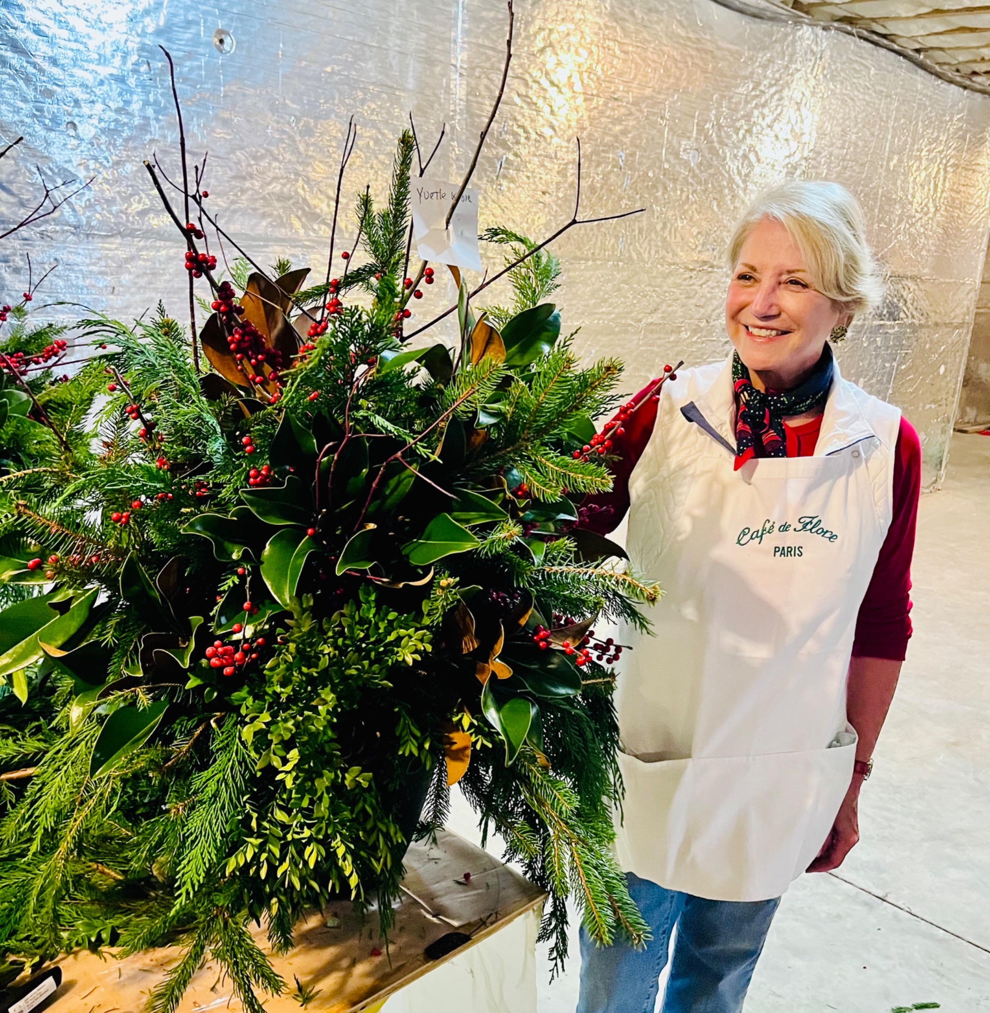 Workshop guest standing beside a full holiday arrangement