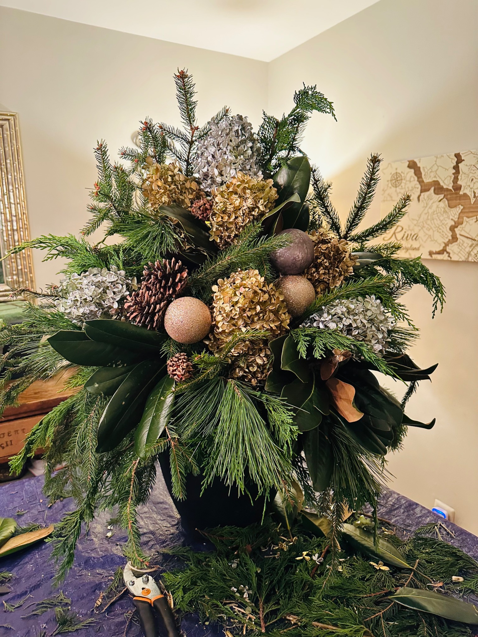 Close-up of a holiday arrangement with evergreen, ornaments, and natural accents