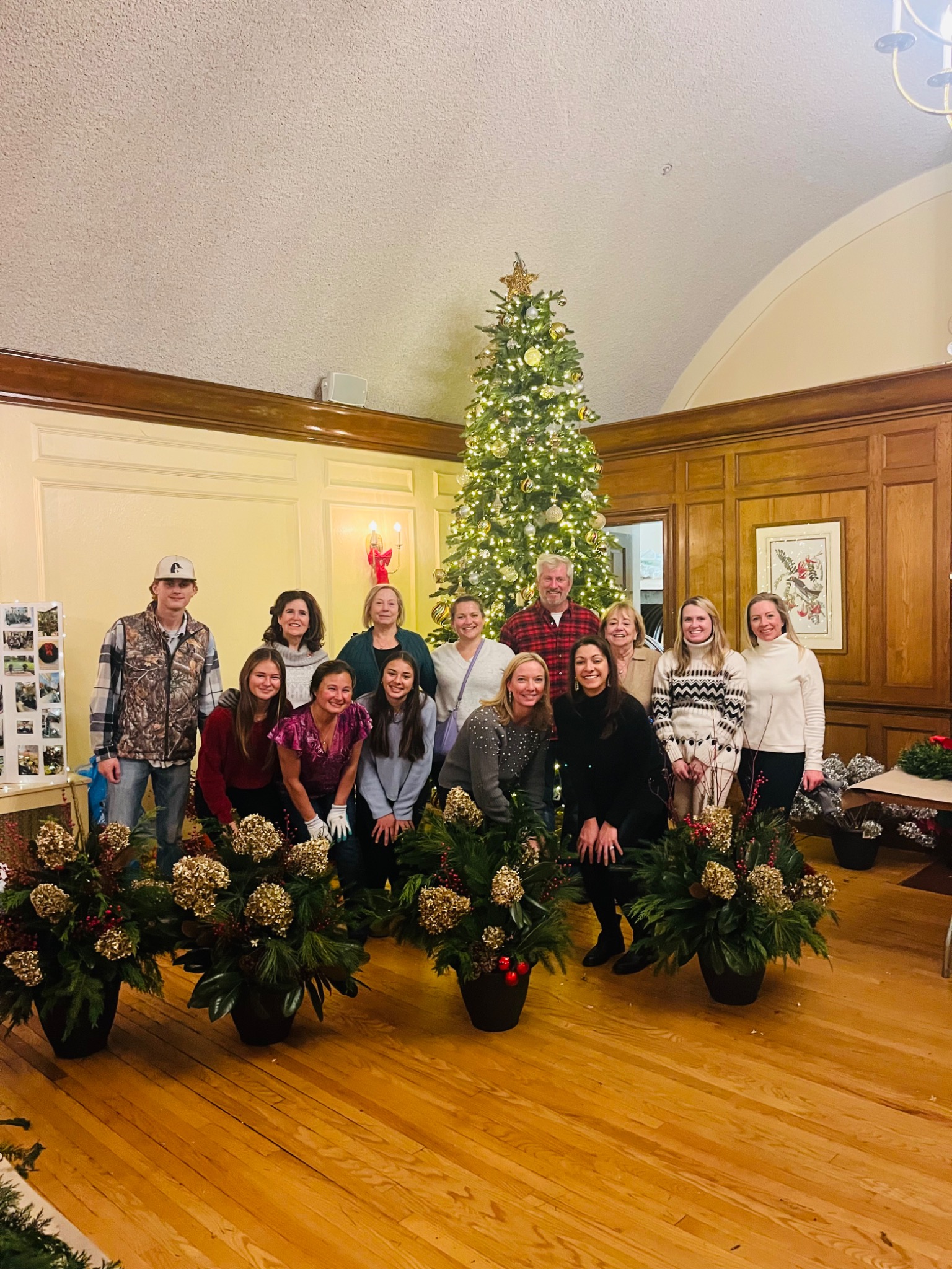 Workshop guests gathered beside the holiday tree with their finished planters