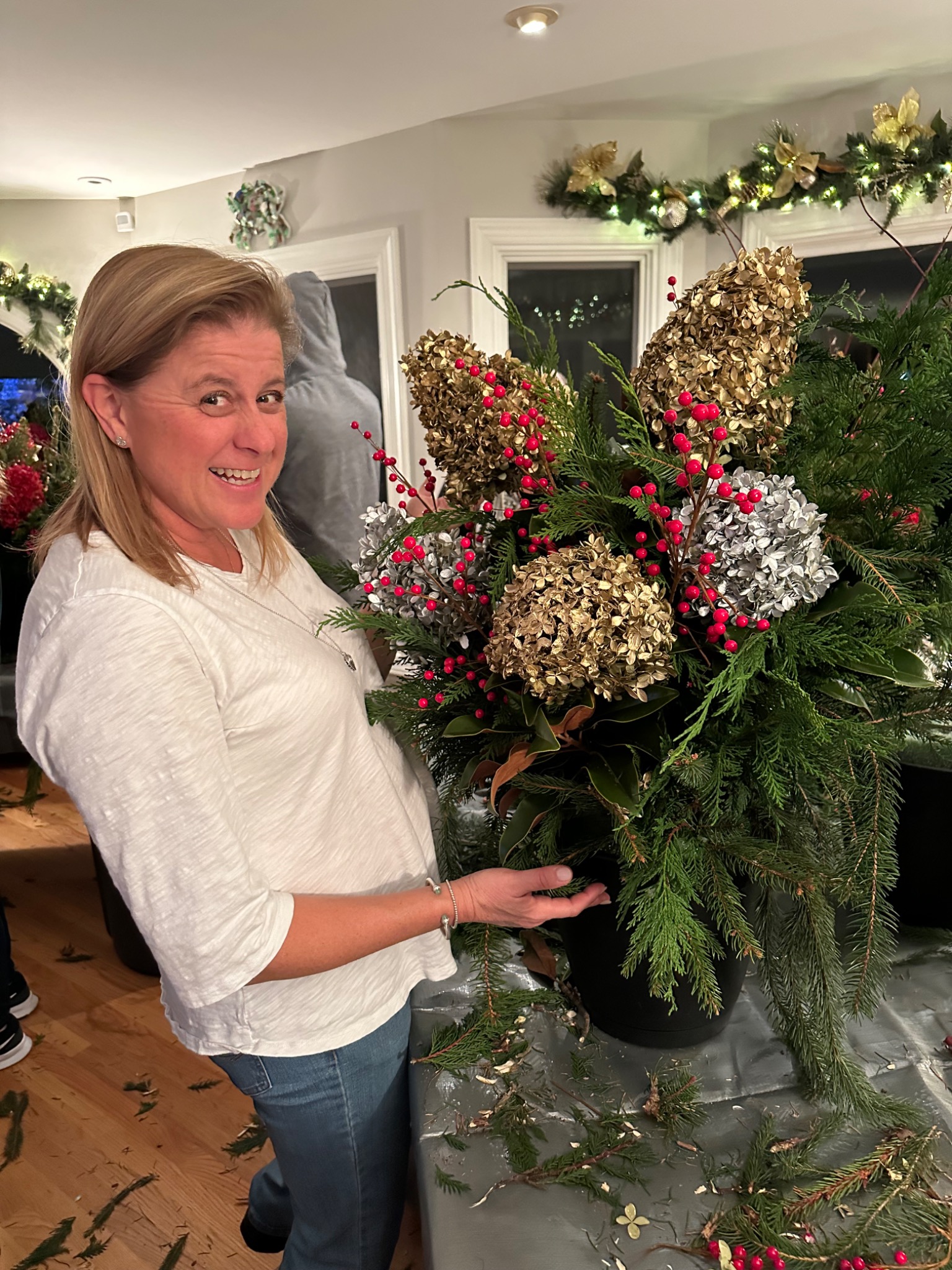 Guest holding a finished red, gold, and evergreen holiday arrangement