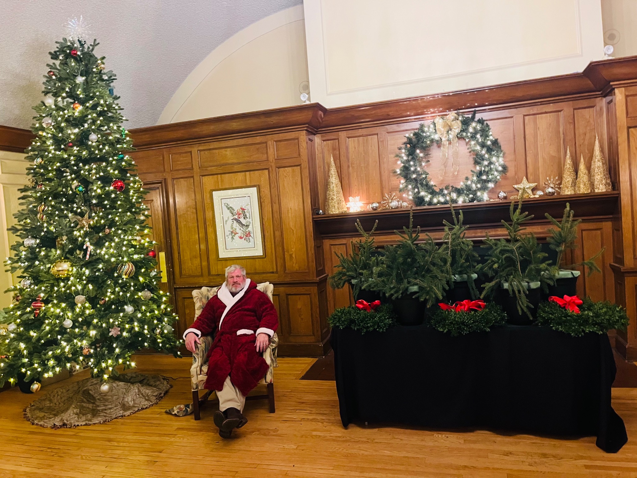Derek dressed as Santa beside the holiday tree and planters