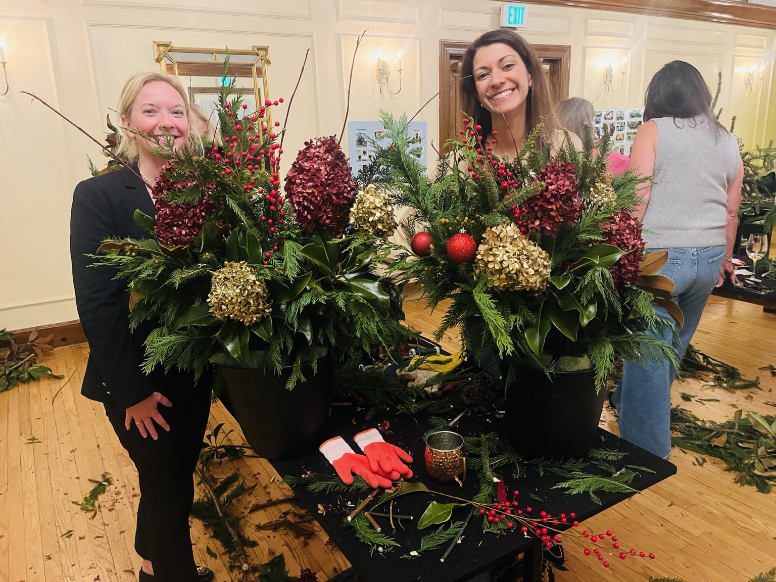 Two guests showing their finished holiday planters at a workshop