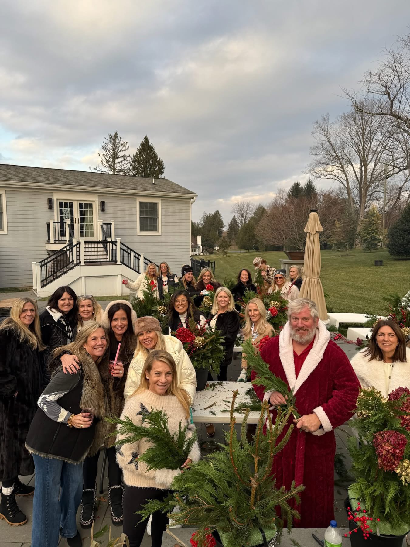 Holiday workshop guests gathered around festive planters with Santa outdoors