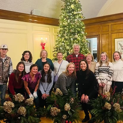 Holiday workshop guests gathered in front of a decorated Christmas tree and evergreen planters