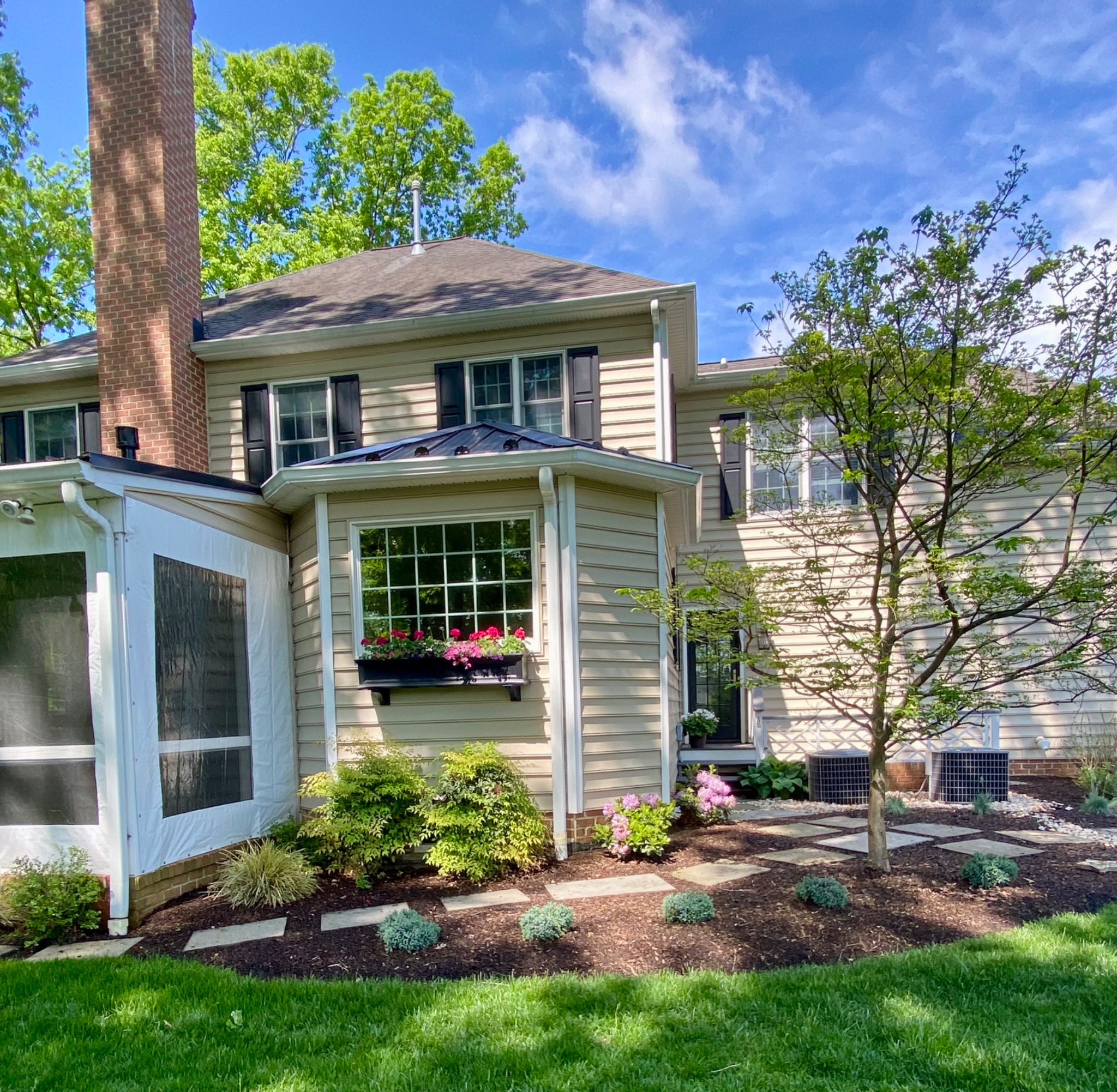 Backyard landscape with a stepping-stone patio, Japanese maple, pink azaleas, and a flower-filled window box