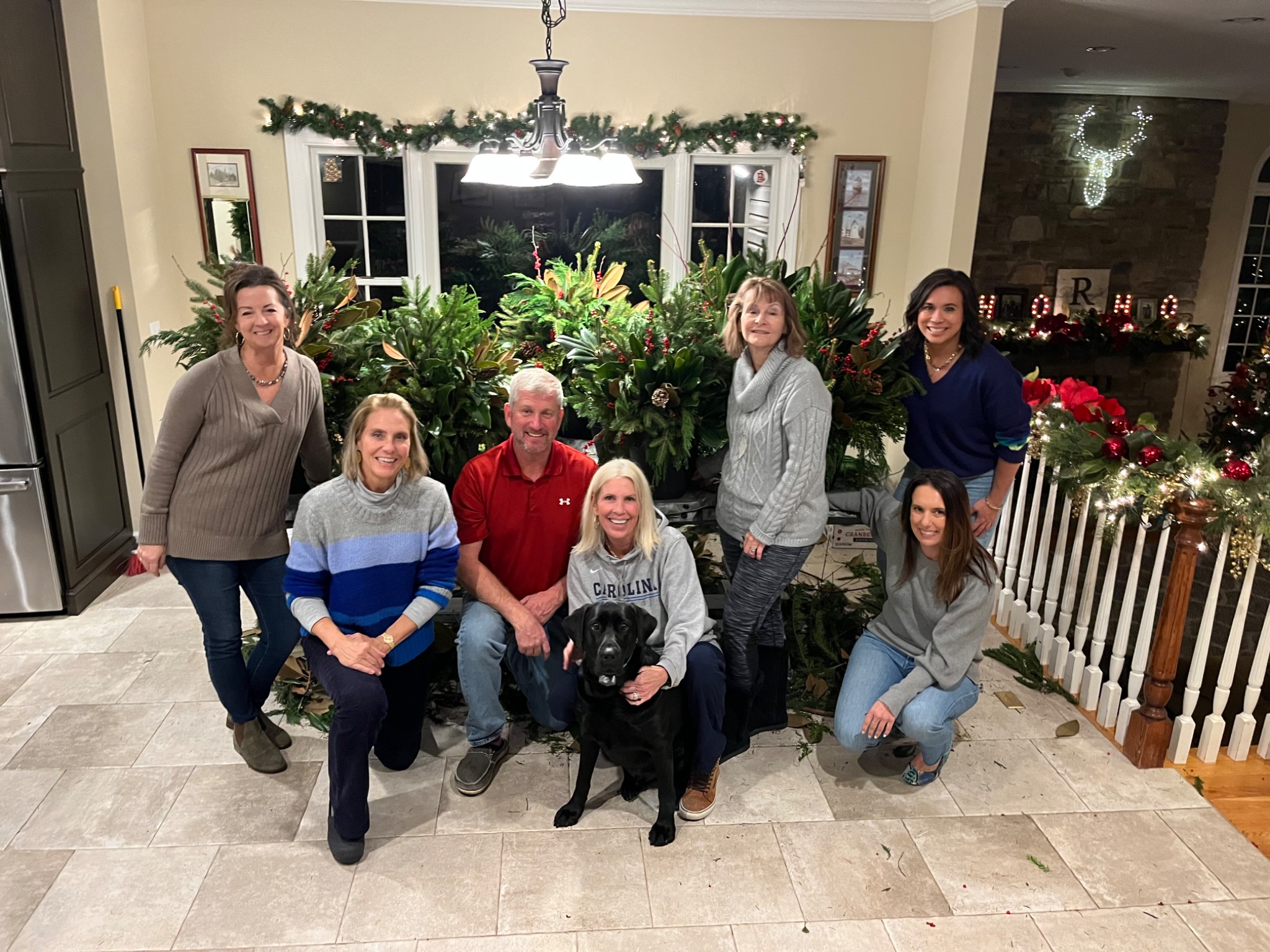 Derek and a group gathered around handmade holiday arrangements at a seasonal container workshop