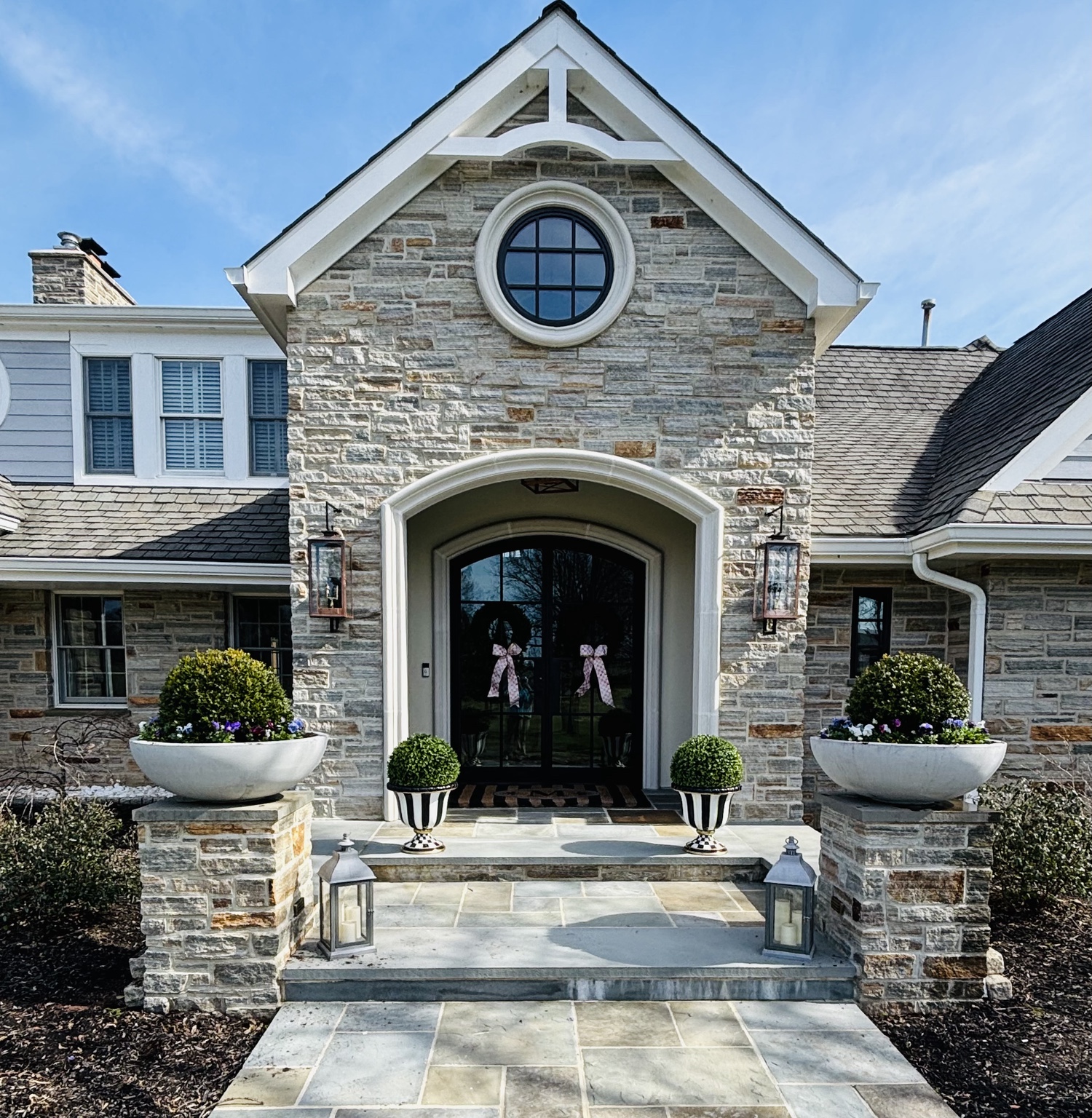 Matching white planters filled with spring pansies flanking a stone front entrance
