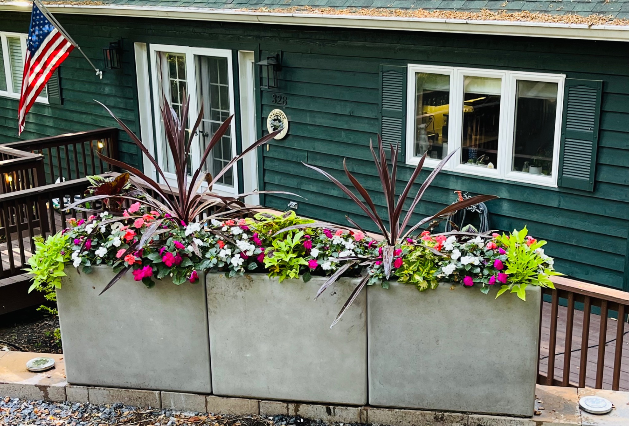 Three long summer planters with colorful flowers arranged along a deck